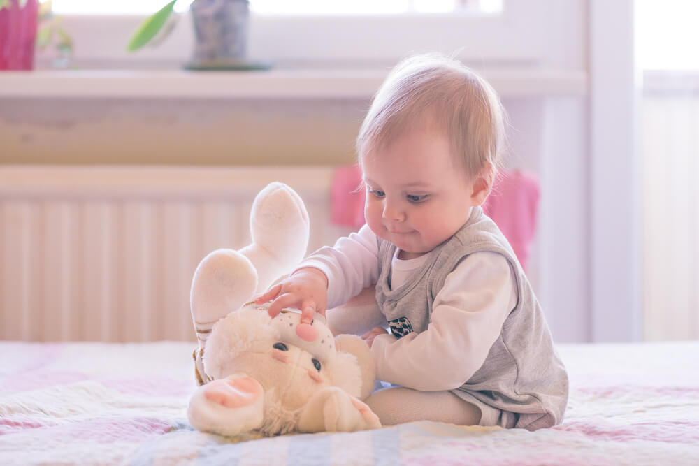 10 months old baby girl playing with a plush bunny