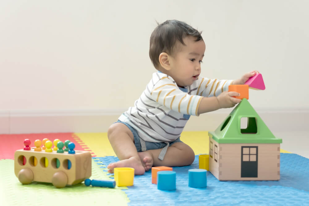 eight month old child reaching for toys